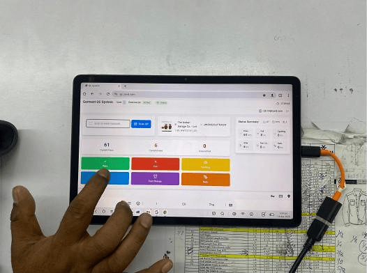 An operator records a garment quality check on a tablet at the factory.